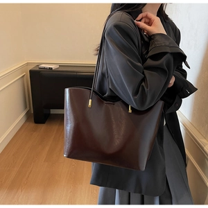 Close-up of deep brown glossy leather tote bag with elegant gold metal buckles