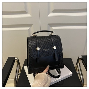 Detail of woven texture black leather backpack with elegant gold circular buckle hardware