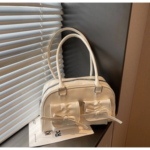 Detailed view of white shiny PU leather Boston bag featuring decorative bow pockets