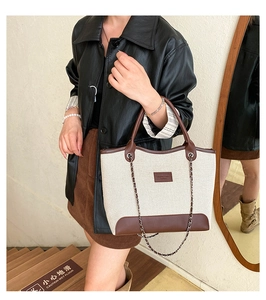 Elegante borsa tote in tela beige con finiture in pelle marrone in un ambiente moderno