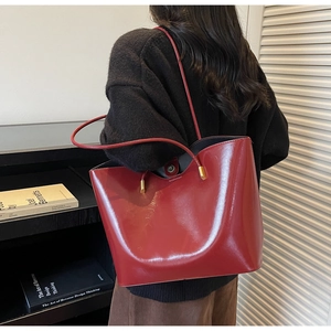 Detail of red glossy leather tote bag with golden metal buckle and spacious interior