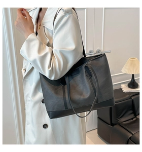 Detail view of the large capacity tote bag in gray and black on a white leather coat