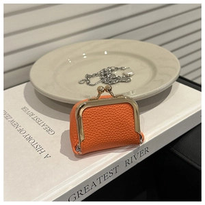 Detalle de mini monedero de cuero naranja con cierre metálico dorado de estilo retro