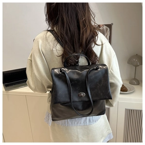 Detail of vintage black faux leather backpack with silver rotating metal buckle closure