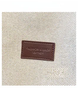 Dettaglio della borsa tote in tela con trama intrecciata beige e toppa in cuoio marrone