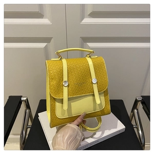 Detail shot of yellow faux leather backpack featuring crocodile texture and silver buckles