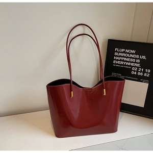 Deep red patent leather tote bag detail with luxury gold hardware and minimalist design