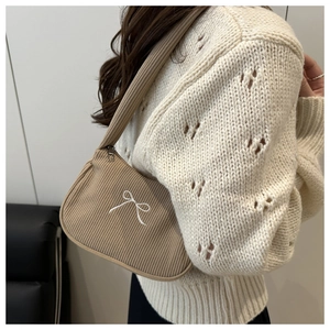 Detail of khaki corduroy texture and white embroidered bow on stylish shoulder bag