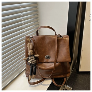 Detail of vintage brown leather backpack with metal clasp and cute knitted bunny charm