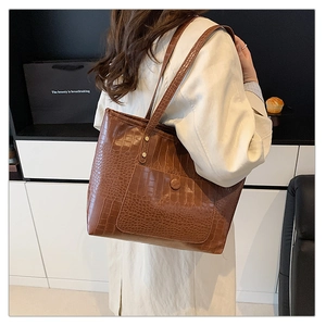 Detail of vintage brown crocodile pattern tote bag with front pocket and gold rivets