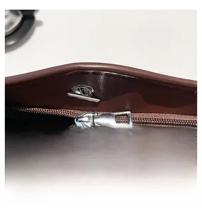 Dettaglio macro della cerniera a due vie in argento e hardware su borsa tote in pelle marrone