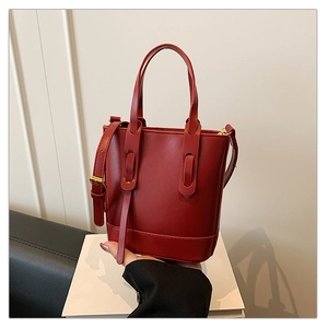 Detail view of burgundy bucket bag with adjustable strap and golden hardware accents