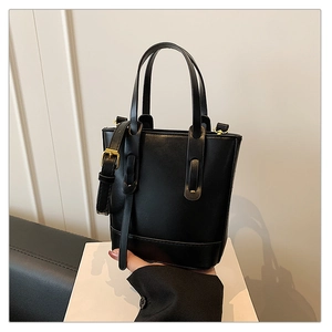 Detail view of the black leather bucket bag showing stitching and metal strap buckle