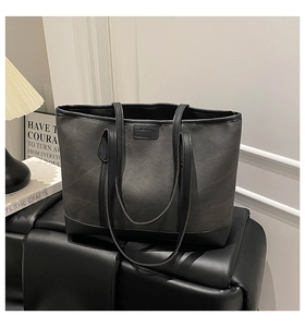 Detail of grey textured fabric tote bag with black leather handle and embossed logo