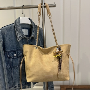 Minimalist apricot suede tote bag with chain strap and cute bear charm shown on a hanger