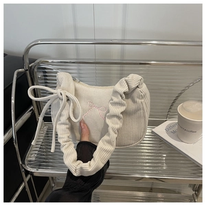 Détail du sac bandoulière en velours côtelé blanc cassé avec broderie nœud rose et anse