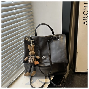 Detail of black faux leather tote bag with elegant turn-lock closure and cute bunny charm