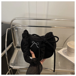 Détail d'un sac à bandoulière en velours noir avec nœud brodé et sangle plissée