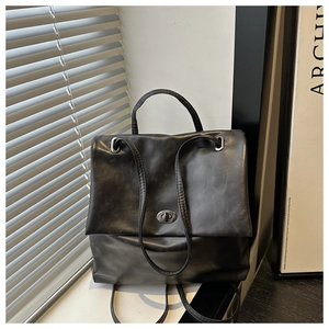 Detail of black oil wax leather backpack with silver twist-lock and matte texture