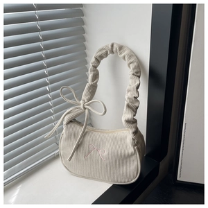 Gros plan du sac hobo en velours côtelé blanc cassé avec broderie nœud et bandoulière