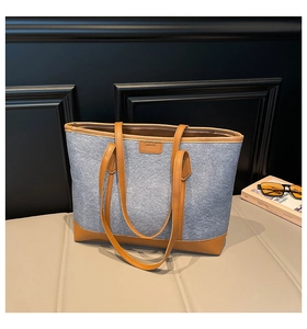 Détail du sac cabas en feutre bleu avec poignées en cuir marron et patch mode gaufré