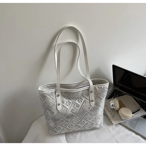 Detail of jacquard weave tote bag with floral patterns and sleek white leather strap