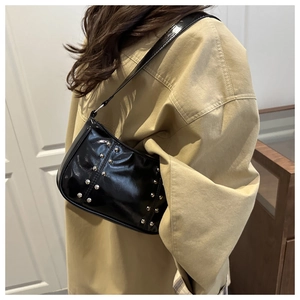 Detail of glossy black shoulder bag featuring silver rivets and sleek vintage texture