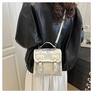Detailed back view of a cream crossbody bag with silver floral prints on a female model