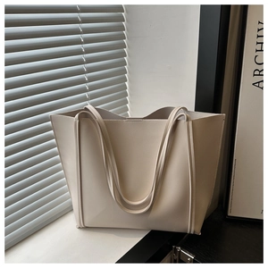 Detail view of cream tote bag with contrast stitching on a minimalist window sill