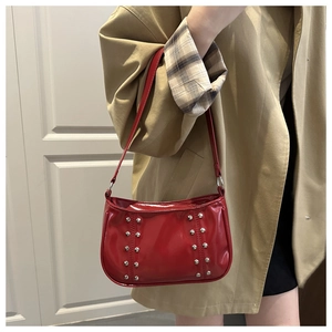 Detail of red patent leather shoulder bag with silver rivets and Y2K style aesthetic