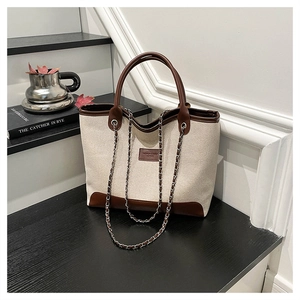 Dettaglio della borsa tote in tela e pelle con tracolla a catena ed etichetta moda