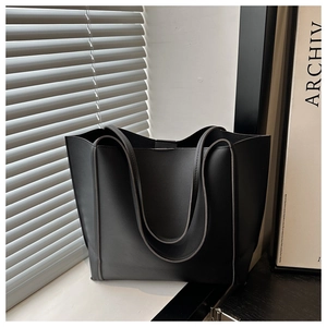 Detail of minimalist black faux leather tote bag with fine texture and dual handles