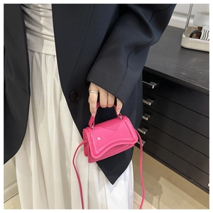 Chic pink glossy mini crossbody bag with wavy flap detail held by a model