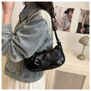 Detail of black punk-style crescent bag with silver buckles and faux leather texture