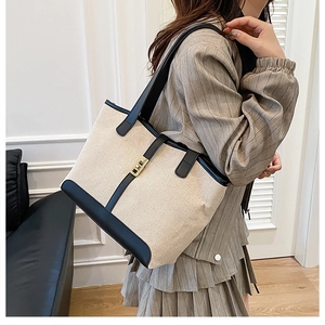 Detailed view of tote bag featuring canvas leather stitching and gold metal lock buckle