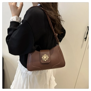 Brown leather underarm bag with gold vintage buckle worn over lace sweatshirt