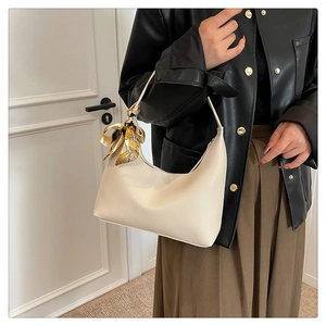 Detail of cream leather hobo bag with yellow silk scarf accessory and pebble texture