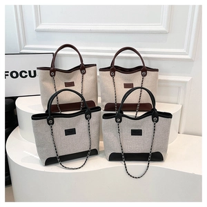 Dettaglio di eleganti borse tote in tweed marrone e nero con manici in pelle