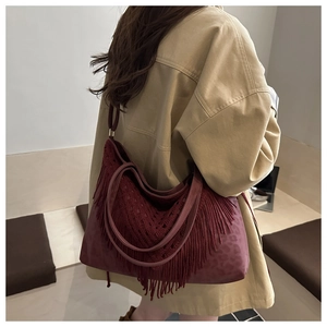 Detail of burgundy tote bag featuring crochet textures and long tassels in a boho style