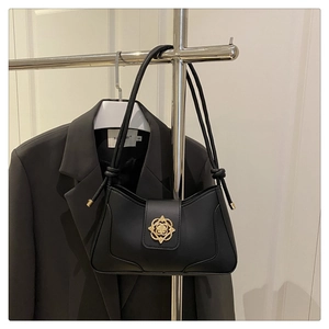 Détail du sac hobo noir avec bandoulière nouée et boucle dorée de style minimaliste