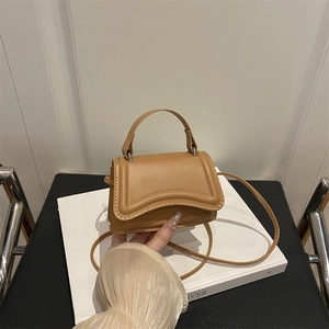 Piccola borsa quadrata minimalista in pelle marrone con patta ondulata e manico