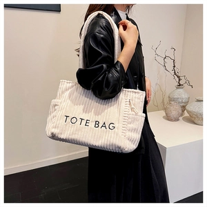 Vue détaillée du sac cabas en velours côtelé crème avec broderie TOTE BAG et poche latérale