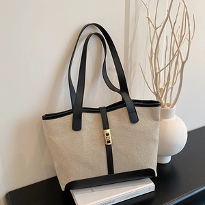 Minimalist canvas tote bag with black leather trim and golden metal clasp for daily use