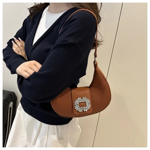 Détail d'un sac demi-lune plissé marron avec boucle en strass et fine bandoulière