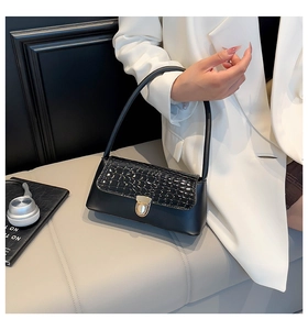 Détail du sac sous le bras noir à motif crocodile et fermoir rotatif doré élégant