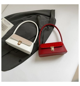 Détail de sacs sous le bras au motif crocodile minimaliste en couleurs crème et rouge foncé