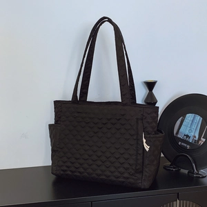 Quilted black puffer tote bag with diamond stitching and side pockets for casual daily use