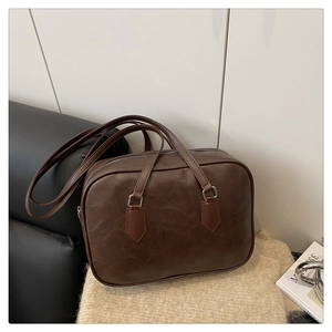 Detail of vintage brown textured leather Boston bag with long handles and zip closure