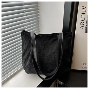 Vue détaillée du sac cabas noir avec texture de tissu froissé et étiquette FASHION