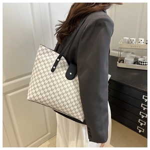 Detail of white tote bag with M-letter monogram print and black leather shoulder strap